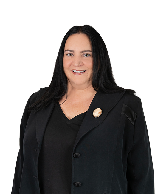 Sacha smiling with her hair down in professional dress, black blazer and blouse and arms at her side.